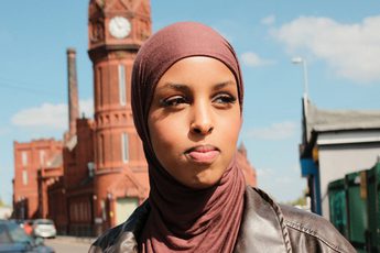 A headshot of a person outside with a building in the backgroud.
