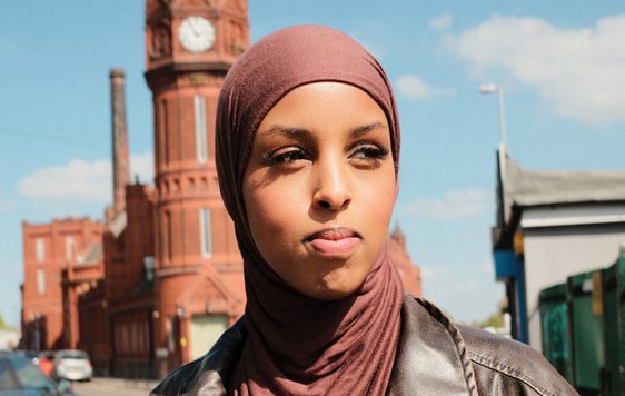A headshot of a person outside with a building in the backgroud.