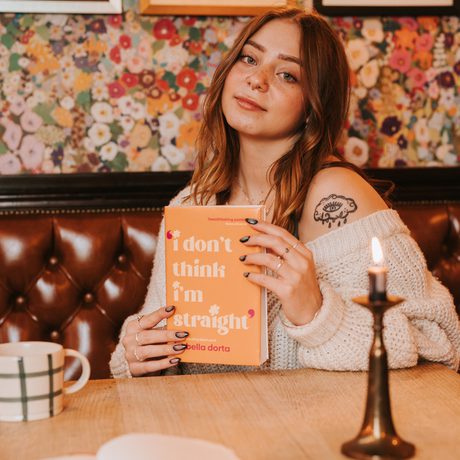 A headshot of a person at a table holding a book.