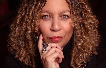 A headshot of a lady resting her hand on her hand.