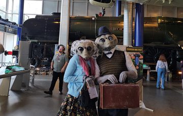 Two people dressed as alien Roswell characters posing underneath the Spitfire.