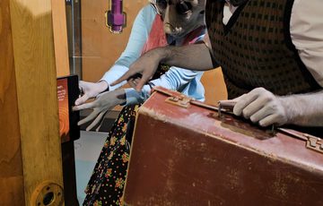 Two people dressed as alien Roswell characters pressing button on an interactive.