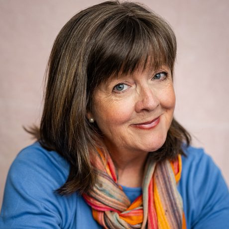 A portrait photograph of a lady wearing a blue top and scarf.
