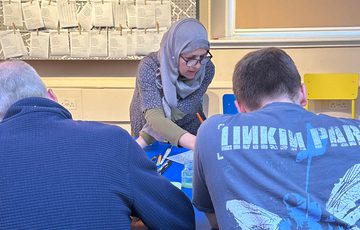 Three people sitting around a table doing a craft activity.