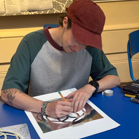A person painting a geometric shape at a table.