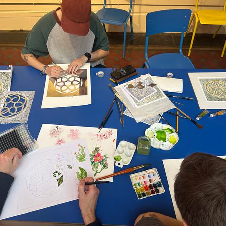 A group of people sitting at a table and painting.