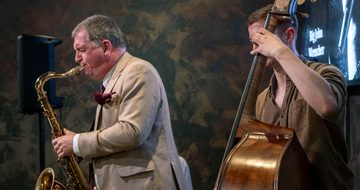 Two musicians performing, one is playing a saxophone and the other a cello.