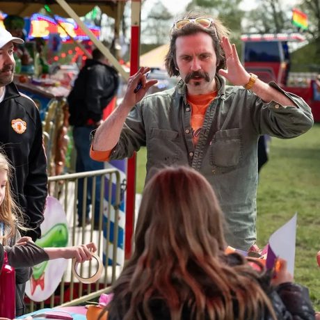 An artist talking to a child, their back of head is shown.