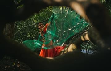 A dancer dancing with a green flowing scarf.