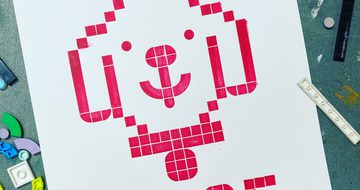 Printed artwork made from LEGO shapes of a dogs head that says woof.