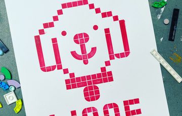 Printed artwork made from LEGO shapes of a dogs head that says woof.