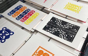 Artwork prints in varies designs and colours laid out to dry.