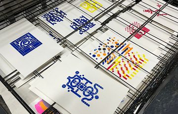 Artwork prints in various designs and colours laid out to dry.