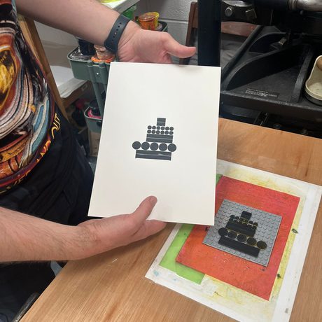 A hand holding an printed paper artwork featuring circles and rectangles.
