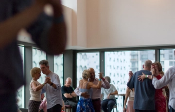 A group of people dancing a in pairs in a modern room.