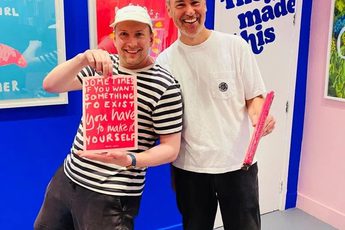 Two people one is holding a screen print.