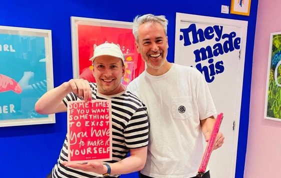 Two people one is holding a screen print.