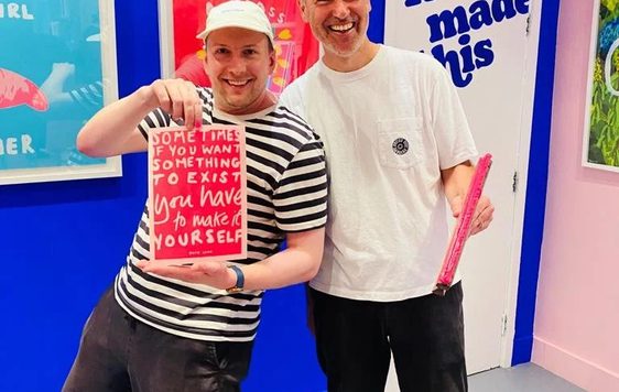 Two people one is holding a screen print.