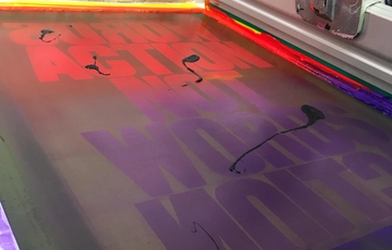 Close up of a printing press with purple and red text.