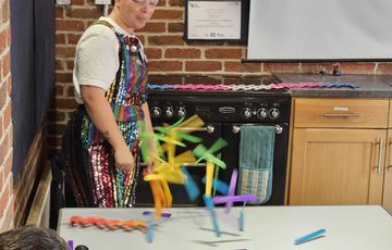 A person doing an experiment with brightly colour sticks on a table.