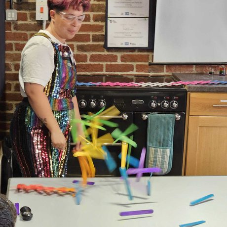 A person doing an experiment with brightly colour sticks on a table.