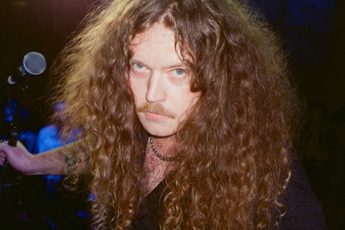 Headshot of Bradley Taylor holding a microphone behind him.