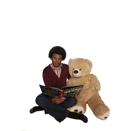 Andy White sitting reading with a large teddy bear, against a white background.