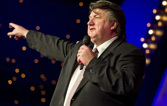 Bob Mills on staging, pointing and holding a microphone.