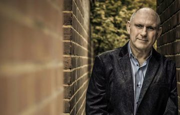 Picture of a man leaning on a brick wall