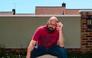 Dave Fensome sitting in a garden with a wall behind.