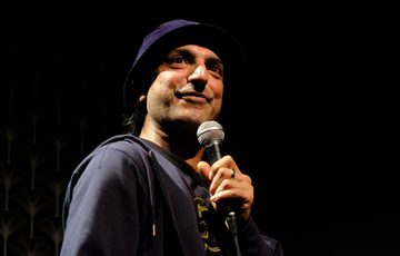 Dharmander Singh performing and holding a microphone.
