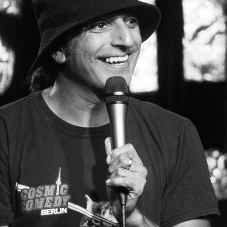 Black and white photo of Dharmander Singh smiling and performing while holding a microphone.