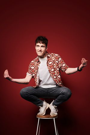 Larry Dean crouching on a stool.