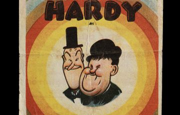 Vintage poster with coloured circles and a cartoon drawing of two men. Text of Stan Laurel, Oliver Hardy and Mi Amigoy40 printed on top
