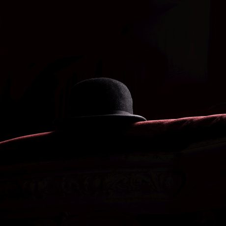Black bowler hat on a red seat against a black background