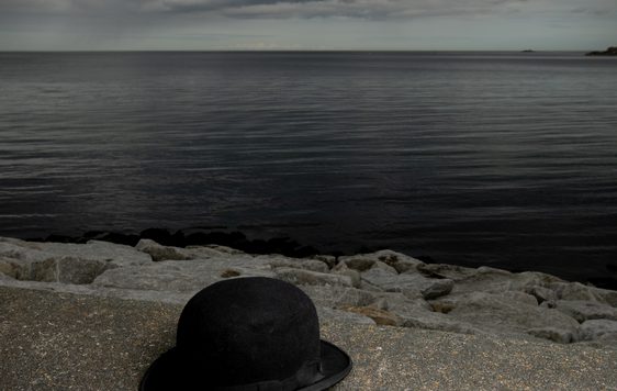 posetr of bowler hat on a sea wall with sea and clouds. Title text in white "The Last Dance of the Cookoos"