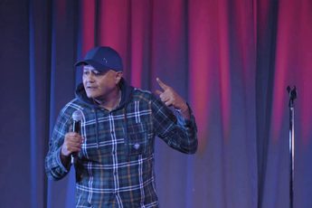 Nik Coppin on stage holding a microphone.