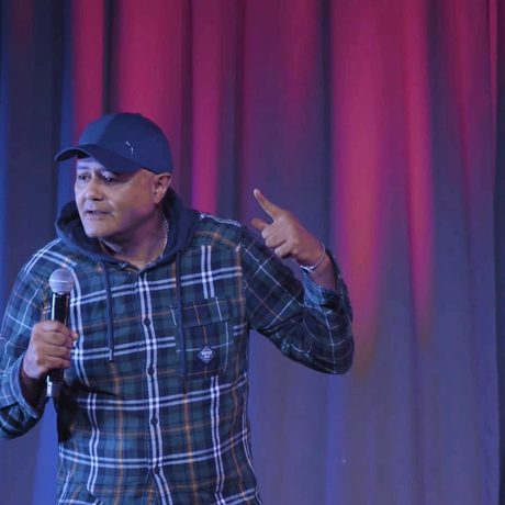 Nik Coppin on stage holding a microphone.