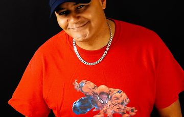Nik Coppin headshot, smiling and wearing a black cap and red t-shirt.