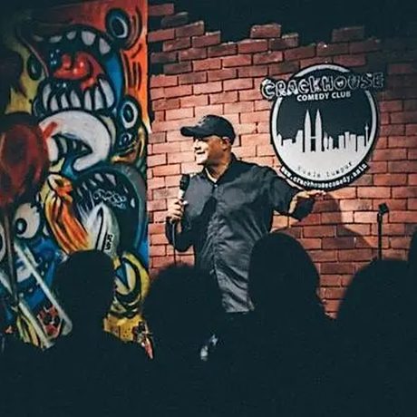 Nik Coppin performing on a stage in front of a group of people.