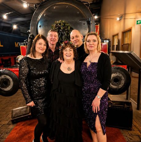 A group of people stand in front of a train in a museum.