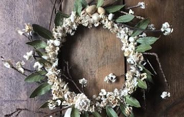 A white and green wreath on a wooden background.