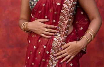 Close up of a woman's torso wearing a red and gold sari dress.