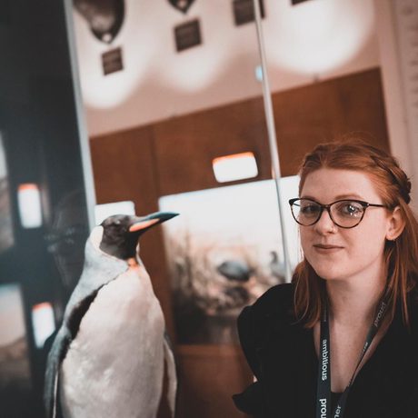 A lady next to a taxidermy penguin.