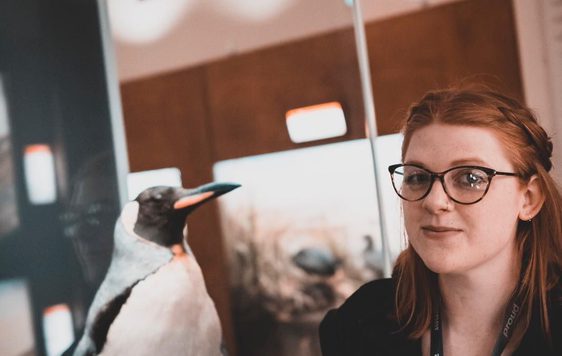 A lady next to a taxidermy penguin.