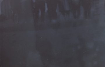 A dark photo where you can just make out people standing.