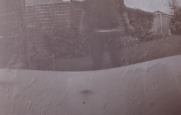 A brown / grey photo of a person outside, the photo is not clear.