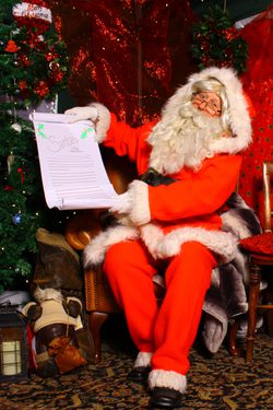 Father Christmas / Santa sat on a chair in grotto holding a list.