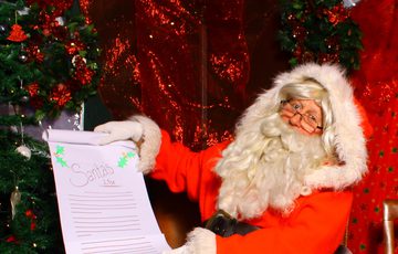 Father Christmas / Santa sat on a chair in grotto holding a list.