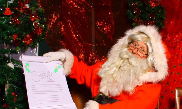 Father Christmas / Santa sat on a chair in grotto holding a list.